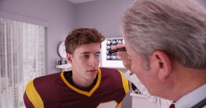 Mid-aged doctor examining football player after concussion.