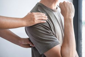 Doctor or Physiotherapist working examining treating injured back of athlete male patient, Doing the Rehabilitation therapy pain in clinic.