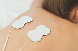 Woman body with electrodes on her back. Electrical muscle stimulation.