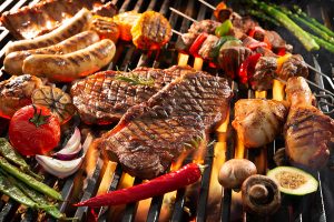 Assorted delicious grilled meat with vegetables sizzling over the coals on barbecue