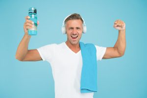 Staying hydrated staying healthy. Healthy and strong man on blue background. Happy athlete celebrate healthy lifestyle. Handsome sportsman smile with water bottle. Healthy and energetic.