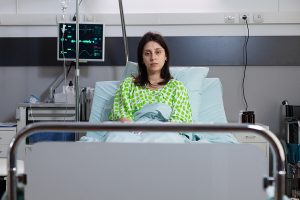 Portrait of sad patient lying in hospital bed recovering after surgery. Hospitalized woman waiting getting healthcare doctor for medical recovery treatment in hospital ward