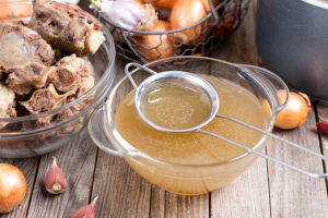 Passing the bone broth through a sieve. Concentrated Bone Broth in a bowl