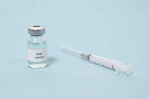 Polio vaccine and syringe on a blue background. Vaccination and prevention poliomyelitis. Infantile paralysis.